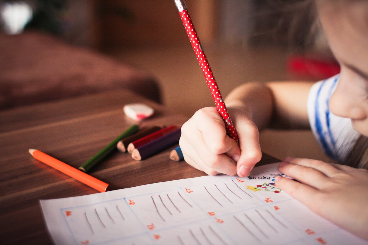 Close-up of a child completing homework using colorful pencils, focused on learning.